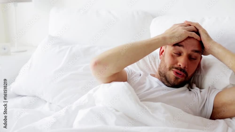 man waking up in bed at home