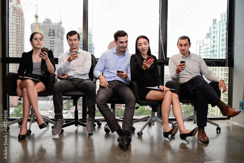 three businessman and two businesswoman relax sit on chair and hold phone at window in the office © shutterdemon