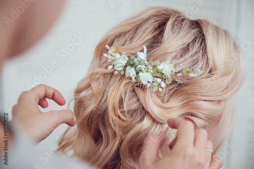 Hair stylist makes styling with hair accessory.