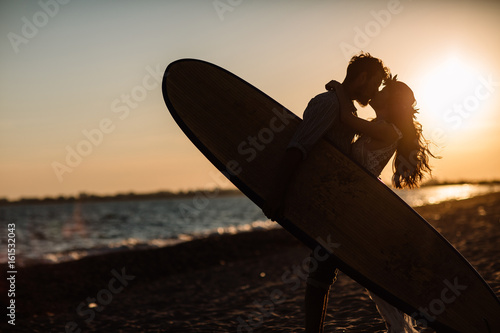 Photography Happy surfers couple standing with surfboards on the sandy beach