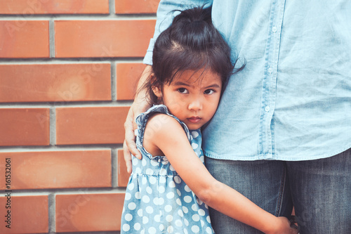 Canvastavla Sad asian kid girl hugging her mother leg in vintage color tone