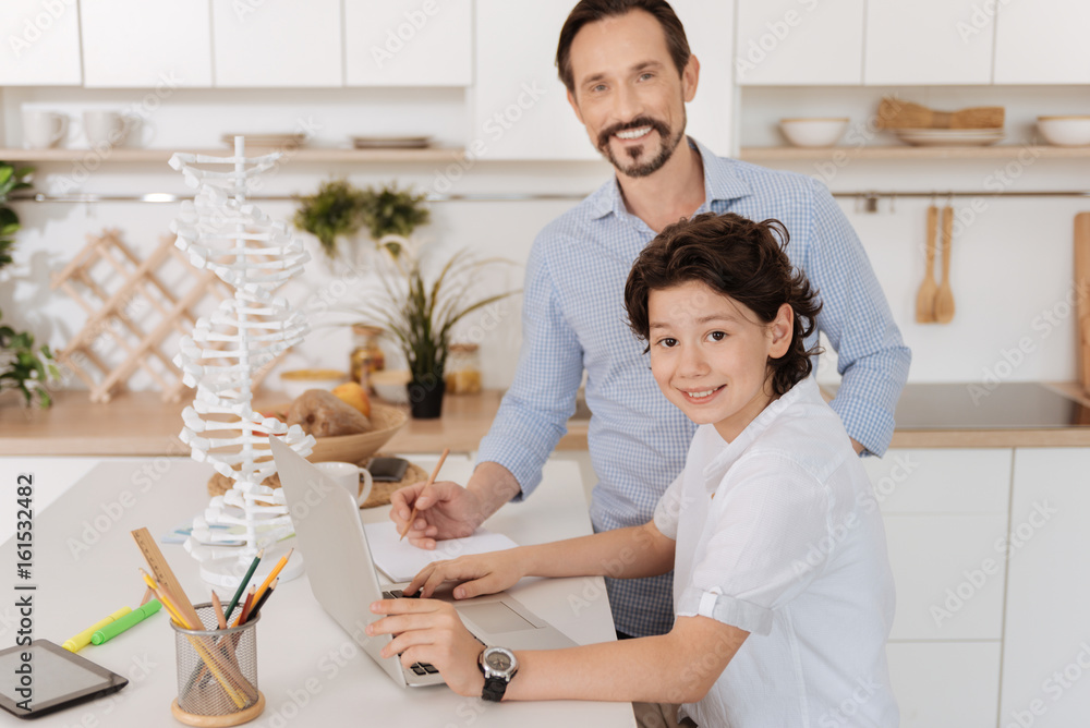 Charming son and his father doing a school project together Charming son and his father doing a school project together