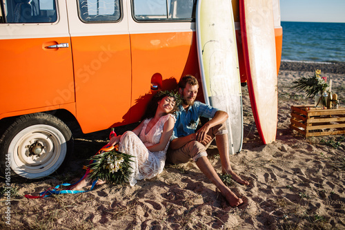 Happy surfers couple standing with surfboards on the sandy beach