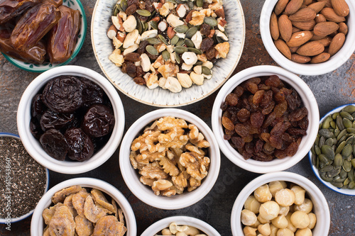 Ingredients for homemade paleo granola, different nuts and raisins, dates, seed on the grey stone background, top view