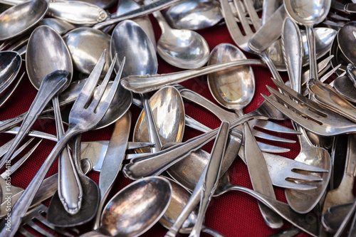 Old silver cutlery, hrown on a background of red fabric