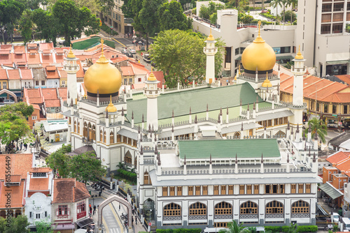 Aerial view of Kampong Glam neighborhood in Singapore with historical Masjid Sultan (or Sultan Mosque), Arab street.  Dense of old style shop houses and modern skyscrapers in background. Day view. photo