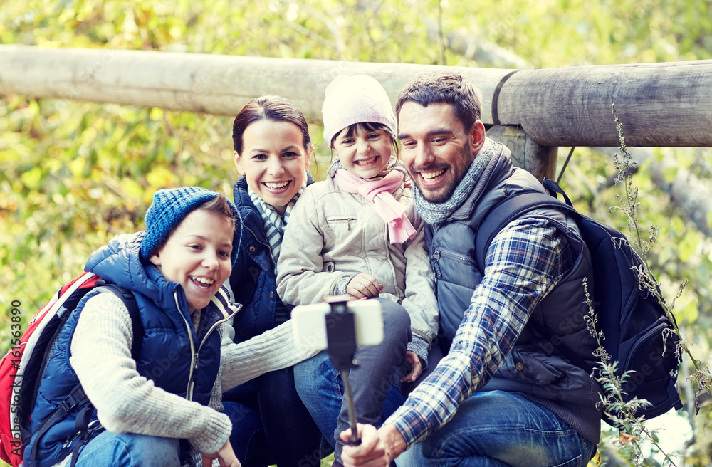 Obraz premium happy family with smartphone selfie stick in woods