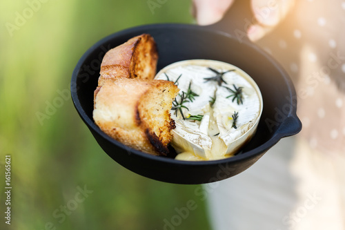Baked camembert cheese  with garlic and rosemary in cast iron skillet