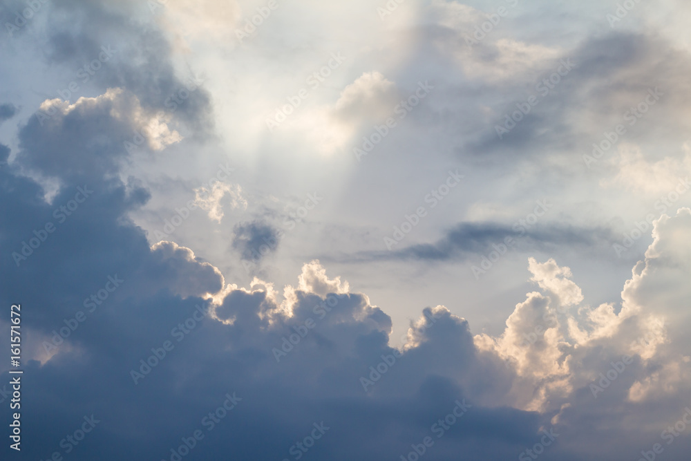 Clouds on blue sky pierced by ray of sunlight, horizontal Clouds on blue sky pierced by ray of sunlight, horizontal