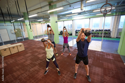 group of people with kettlebells exercising in gym