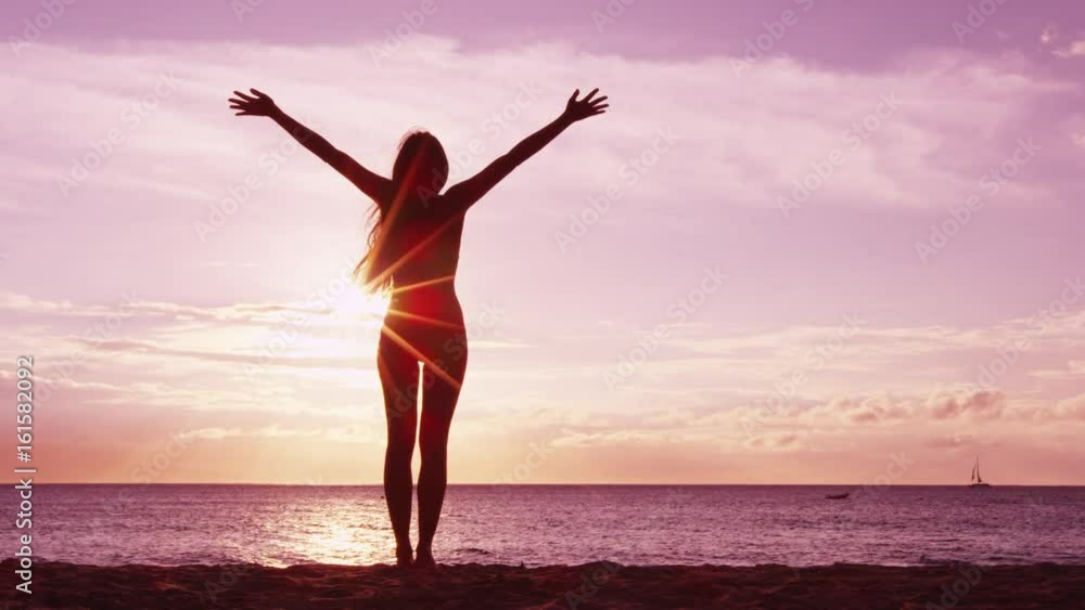 Happiness, freedom and success - Happy serene blissful woman raising arms up at amazing sunset at beach. Young woman enjoying the idyllic serenity. RED EPIC SLOW MOTION. Happiness, freedom and success - Happy serene blissful woman raising arms up at amazing sunset at beach. Young woman enjoying the idyllic serenity. RED EPIC SLOW MOTION.