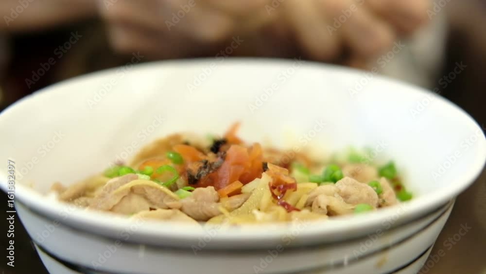 woman's hand eating grilled pork with rice in a bowl in japanese restaurant woman's hand eating grilled pork with rice in a bowl in japanese restaurant