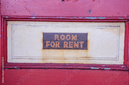 Room For Rent sign on a depalidated dusty door.