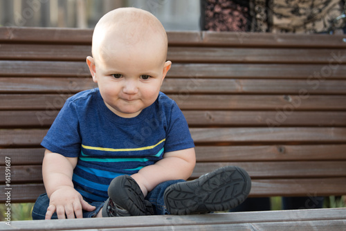 Baby Boy Sitting on Park Bench in Garden