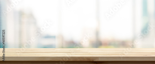 Wood table top on blur  city building view background looking through glass window, panoramic banner photo