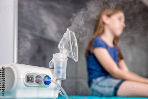 Little girl waiting for medical inhalation treatment with a nebulizer photo