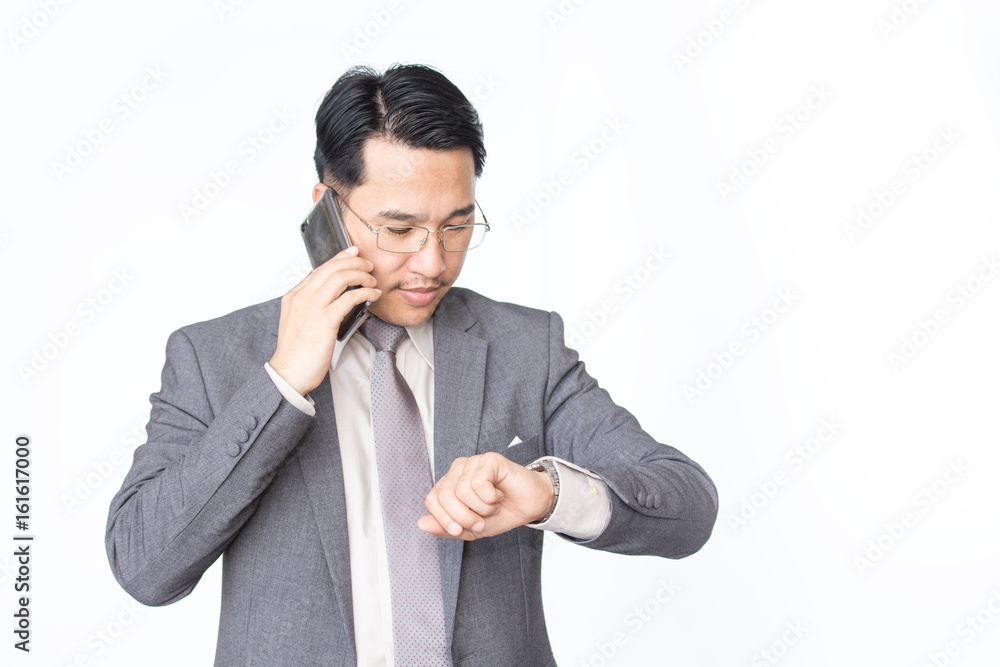 Asian businessman looking wacth while using smartphone, isolated on white background. Asian businessman looking wacth while using smartphone, isolated on white background.
