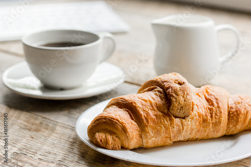 Business breakfast in office with coffee  milk and croissant on wooden table background