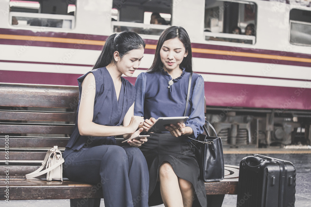Fototapeta premium Two asian woman using tablet at outdoor place with attractive smiling, woman resting concept.