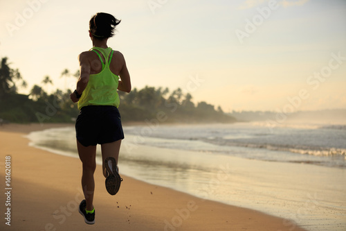 young fitness woman runner running on sunrise beach