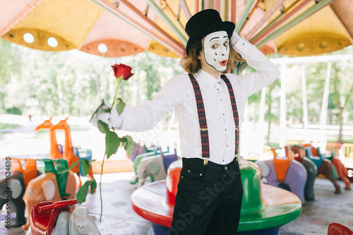 A funny pantomime from a circus rides a swing.