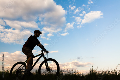 Mountain biker cycling silhouette over blue sky
