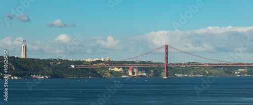 Panoramic view of the 25 de Abril suspension bridge connecting the city of Lisbon, capital of Portugal, to the municipality of Almada on the left bank of the Tagus River on a clear day