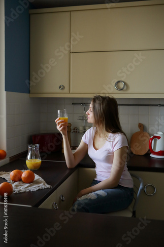 Woman in the kitchen holding a glass of orange juice, a healthy lifestyle