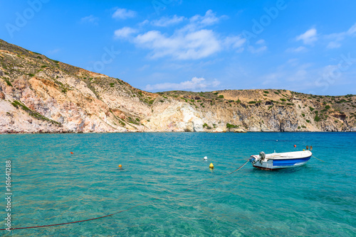 White boat anchoring in beautiful Firopotamos bay with emerald green sea water, Milos, Cyclades Islands, Greece.
