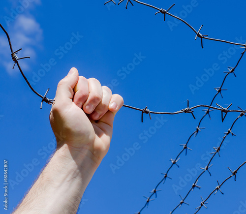 Hand is tearing wire against the blue sky