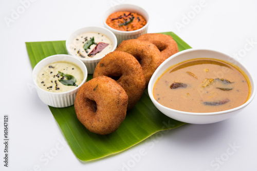 south indian food called vada sambar or sambar vada or wada, served with coconut, green and red chutney over fresg banana leaf, selective focus