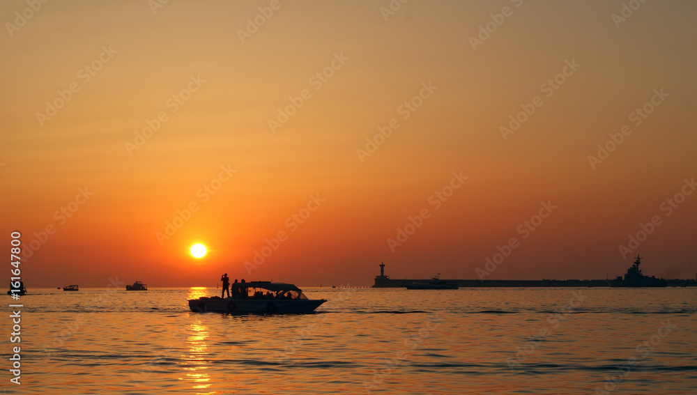 Sunset at sea in the summer. Several boats in the sea.