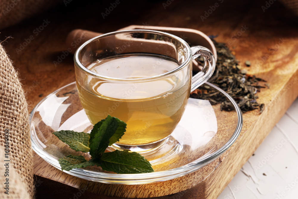 Cup with green tea on brown wooden background with mint leaves Cup with green tea on brown wooden background with mint leaves