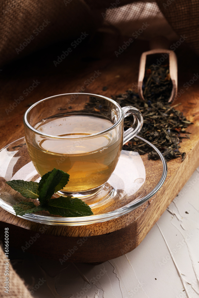 Cup with green tea on brown wooden background with mint leaves Cup with green tea on brown wooden background with mint leaves