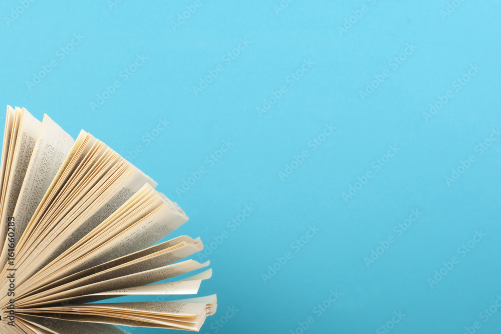 Obraz premium Open book close-up on the background of blue wall. Education background. Back to school. Copy space for text.