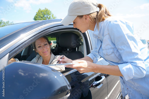 Woman stopping car driver for customer survey