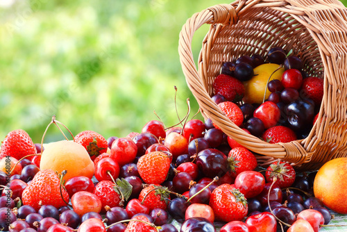 Strawberry, apricots, cherries, gooseberries poured out of the basket. Summer still life.
Many fruits and berries. Blurred background.