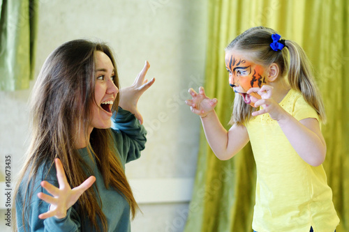 Adorable little girl painted like tiger playing with animator