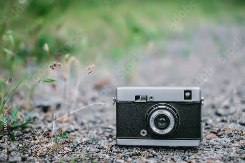 Old retro Camera on the road with grass background.
