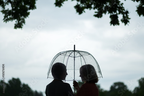 Two women walking park in rain and talk. Friendship and people communication. Rainy photo