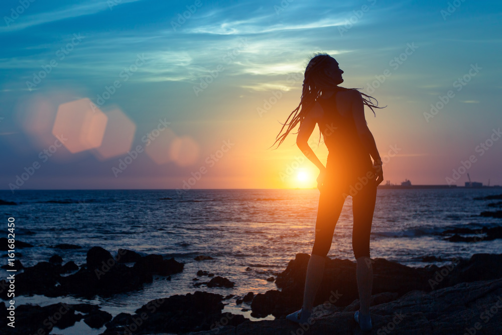 Silhouette of flexible girl on the sea coast during a amazing sunset.