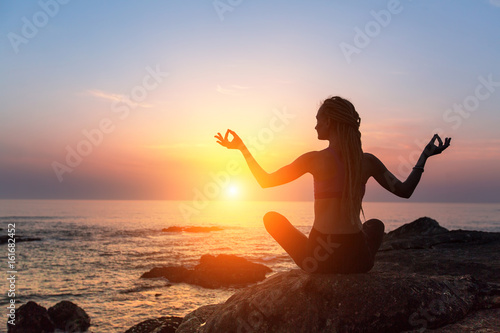 Yoga meditation silhouette. Healthy lifestyle. Fitness woman on the ocean during amazing sunset. © De Visu