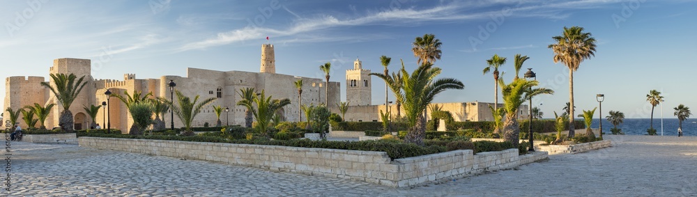panorama with old fort and palm trees with blue sky in Tunisia