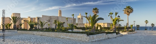 Photo panorama with old fort and palm trees with blue sky in Tunisia