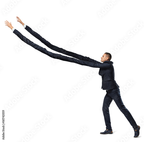 A businessman on white background in side view with extremely long arms trying to grab something above. photo