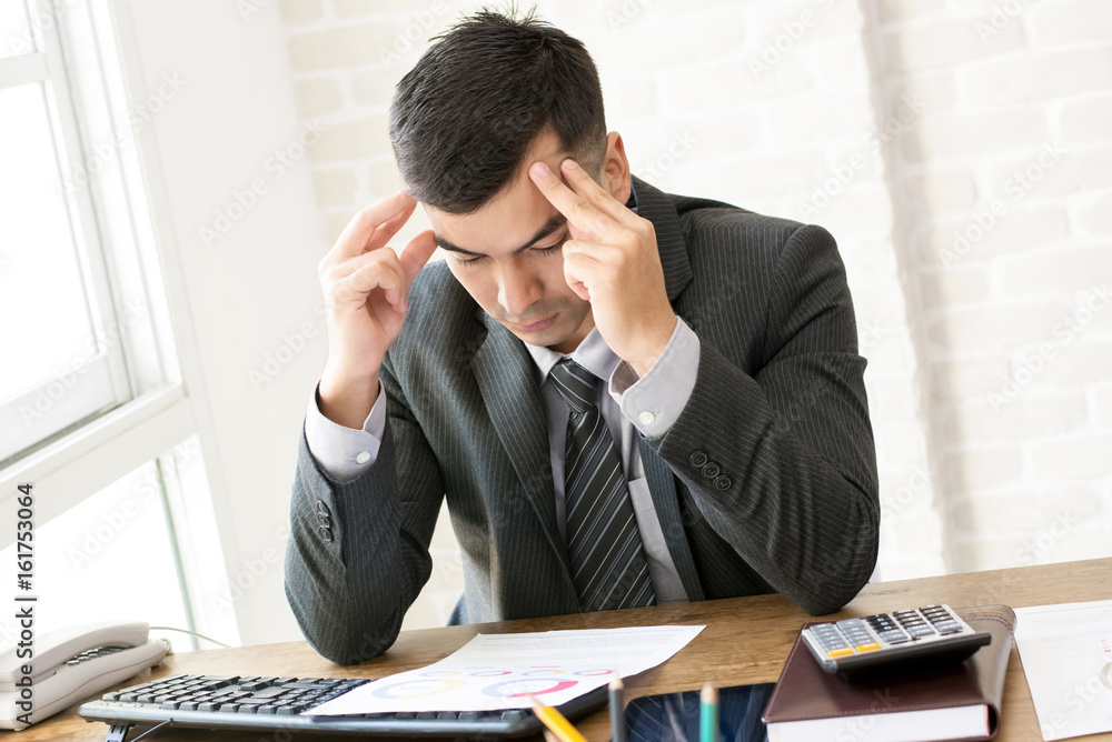 Serious businessman looking at financial document at working table Serious businessman looking at financial document at working table