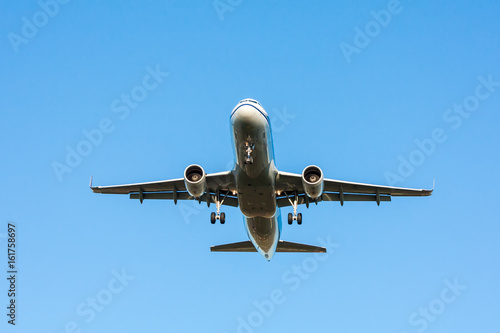 Passenger airplane in flight with landing gear released on blue sky background