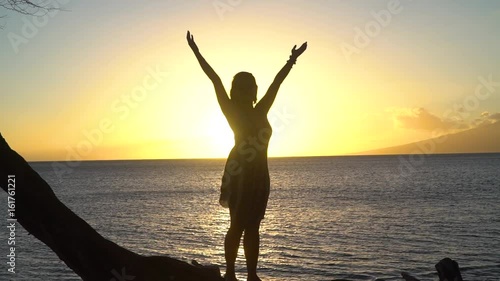 Woman raising hands in the air at sunset in Maui Hawaii