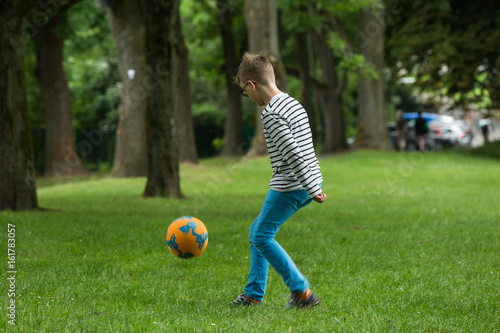 Jugendlicher / Heranwachsender / Junge / Kind spielt mit Fussball auf grüner Wiese / Wald