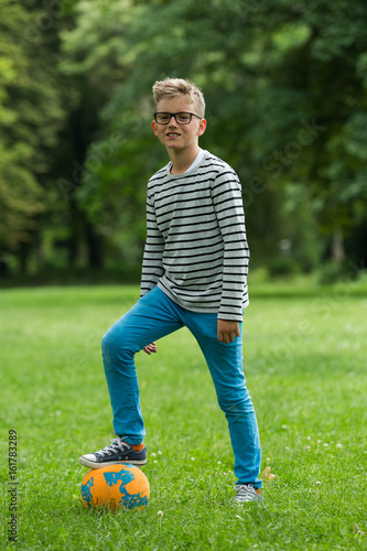 Jugendlicher / Heranwachsender / Junge / Kind spielt mit Fussball auf grüner Wiese / Wald photo